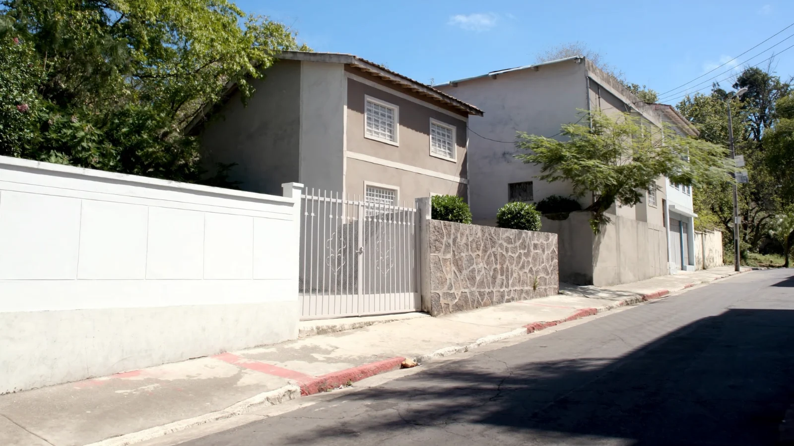 Rua inclinada de bairro residencial com casas assobradadas